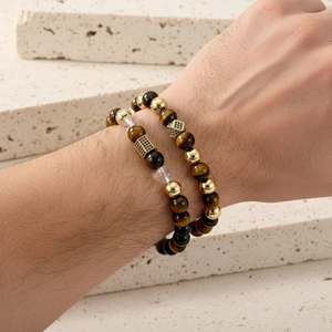 Detail of beaded bracelet set with tiger eye stones and gold zircon crown on stone