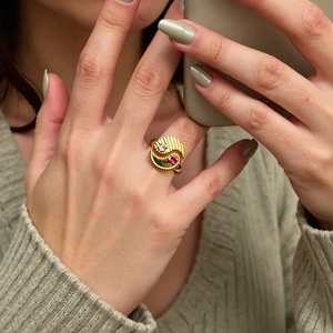 Detail of a gold Tai Chi ring with sunburst and dotted textures featuring zircon and ruby