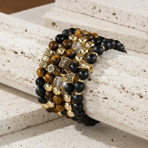 Detail of layered crown bracelets with tiger eye stones and matte black onyx beads