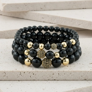 Close-up of black matte crown beaded bracelet set with gold cubic zirconia charms