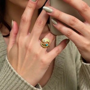 Detail of gold-plated wavy ring with vertical texture, white zircon and turquoise stone