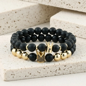 Macro shot of matte black and gold beaded bracelets with micro-paved zircon crown charms