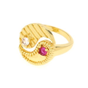 Detail of gold-plated Yin Yang ring featuring red gem and zircon on white background