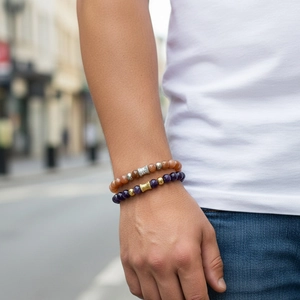 Detail of layered beaded bracelets featuring blue lapis and amber stones on a model's wrist