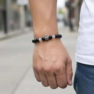 Detailed shot of beaded bracelet with black stones and diamond anchor charm on wrist