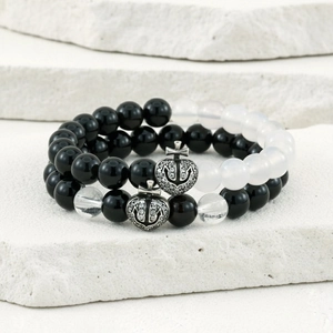 Macro detail of beaded heart cross charm bracelet set on natural white stone base