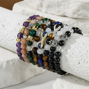 Detailed view of layered beaded bracelets with natural stone beads and crown charms