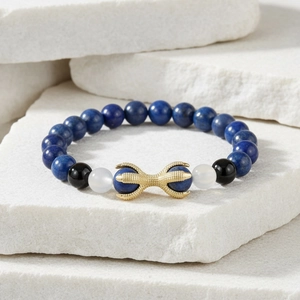 Detailed shot of Lapis Lazuli beads and a golden eagle claw charm on stone background