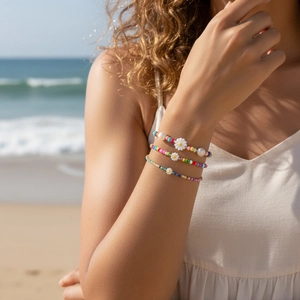 Dettaglio di set di braccialetti boho con perline colorate e margherite su sfondo spiaggia