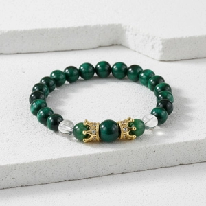 Detail of green tiger eye beads and golden zircon crown charms on a beaded bracelet