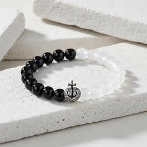 Detailed macro view of black and white beads bracelet with silver anchor heart cross charm