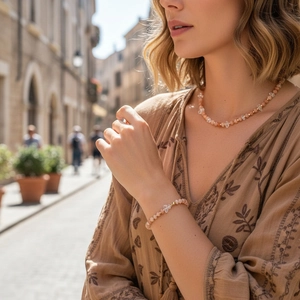 Detail van kralenketting en armbandset met roze stenen en kristallen vlinder