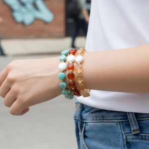 Detailansicht von drei handgefertigten Perlenarmbändern mit weißen Perlen am Handgelenk.