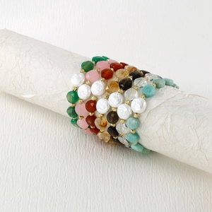Details von bunten Perlenarmbändern mit Natursteinen und Metallzwischenteilen auf weißer Rolle
