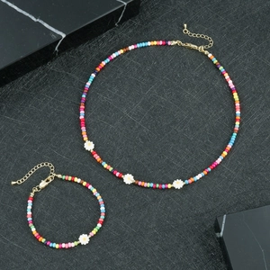 Dettaglio di set collana e bracciale di perline colorate con margherite e chiusure dorate