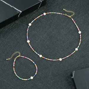 Dettaglio del set collana e bracciale di perline colorate con margherite su fondo nero