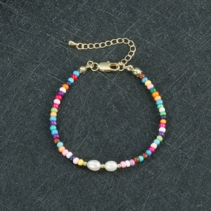 Dettaglio di un bracciale di perline colorate con due perle e chiusura d'oro regolabile