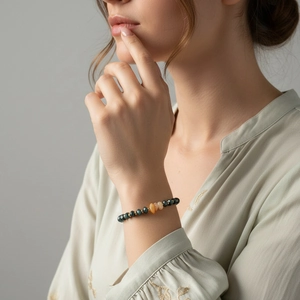 Detail van natuurstenen kralenarmband met oranje ruwe stenen om een vrouwenpols