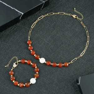 Makro-Detail von Goldkette und Armband-Set mit roten Perlen und weißem Perlen-Akzent