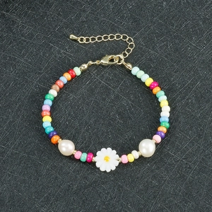 Vista macro del bracciale di perline colorate con ciondolo a margherita e chiusura oro