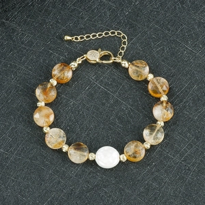 Detail eines Perlenarmbands mit gelben Kristallperlen, Perle und verstellbarem Goldverschluss