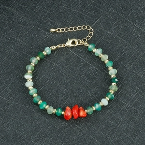Detail van kralenarmband met groene gefacetteerde kralen en rode koraalsteen elementen