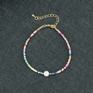 Dettaglio del bracciale di perline colorate con ciondolo a margherita e chiusura dorata