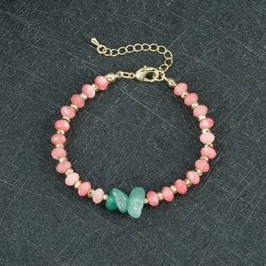 Detail van een kralenarmband met groene ruwe stenen en roze kralen met gouden sluiting