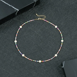 Dettaglio della collana bohémien di perline colorate con ciondoli a margherita su marmo nero