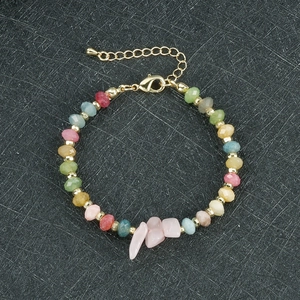 Detail van gekleurde facetparels en onregelmatige roze stenen op een gouden armband