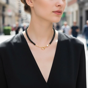 Collier élégant en perles d'onyx noir avec une perle blanche et un fermoir doré