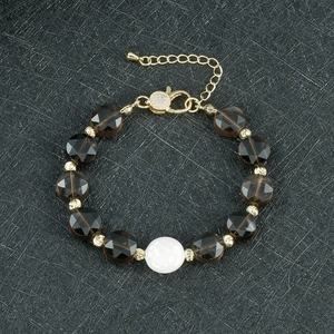 Detailaufnahme eines Perlenarmbands mit rauchbraunen Kristallen und Muschelmitte auf Schwarz