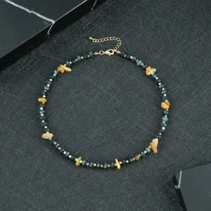 Detail van kralenketting met blauwe gefacetteerde stenen en goudkleurige karabijnsluiting
