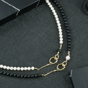 Détail d'élégantes perles noires et blanches avec un fermoir asymétrique plaqué or unique