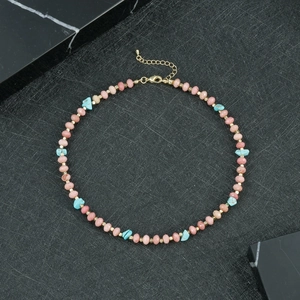 Detail van handgemaakte kralenketting met roze kristallen en blauwe turquoise steen