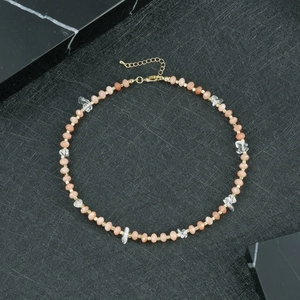 Detailopname van perzik kralenketting met kristallen en een gouden sluiting