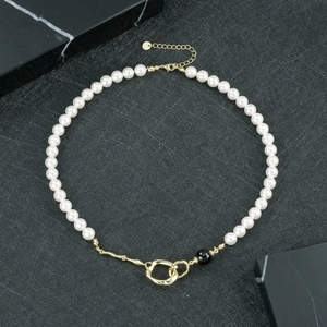 Détail d'un collier en perles d'eau douce avec onyx noir et fermoir en métal doré fluide