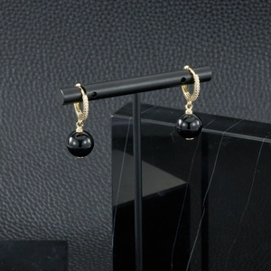 Détail de boucles d'oreilles dorées avec perles onyx noires et cristaux étincelants