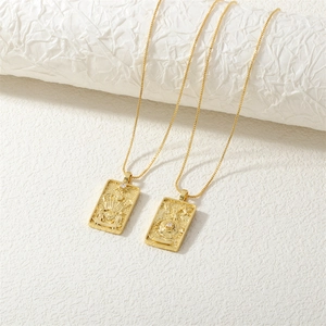 Macro shot of gold tarot pendant necklaces with embossed designs and zircon stones