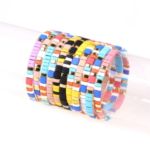 Close-up of colorful enamel beaded elastic bracelets with golden metal spacers in detail