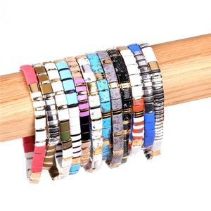 Detailed macro view of colorful enamel Tila bead elastic bracelets on a wooden display