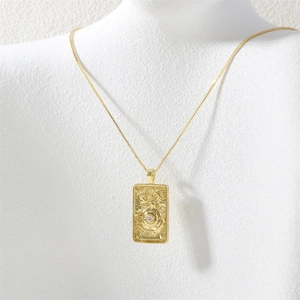 Detail of gold Wheel of Fortune tarot necklace with zircon on a white textured bust