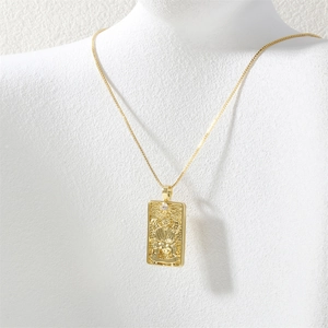Detail of gold tarot card pendant necklace with embossed angel on white mannequin