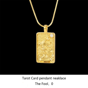 Macro detail of gold tarot card necklace featuring the engraved Fool design on black background