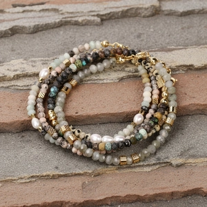 Detail van gelaagde natuurstenen kralenarmbanden met zoetwaterparels en goudkleurige sluitingen
