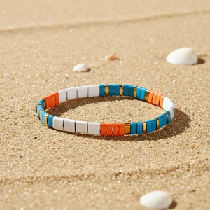 Dettaglio del bracciale di perline Tila colorate con tessere bianche arancioni blu e oro