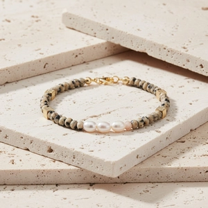 Detailweergave van zoetwaterparels en stenen kralen op de vergulde armband
