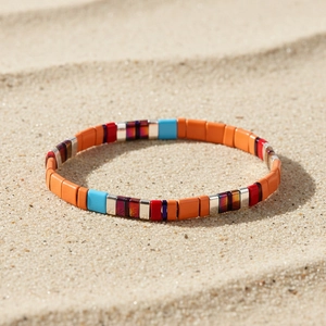 Dettaglio del braccialetto colorato di perline Tila con motivo etnico sulla spiaggia