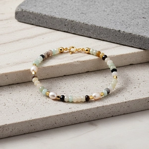 Macro-opname van veelkleurige halfedelstenen en zoetwaterparels armband met gouden sluiting