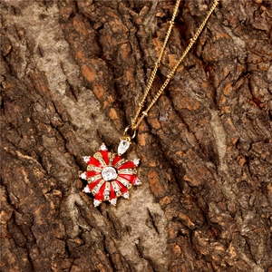 Dettaglio del ciondolo a girasole dorato con smalto rosso, cristallo bianco e catena